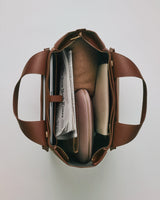 Open travel bag with contents including a newspaper, and various neatly arranged items.