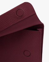 Close-up view of an open textured leather bag with snap button closures.