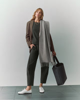 Person in suit holding a large tote with a scarf draped over their shoulder.