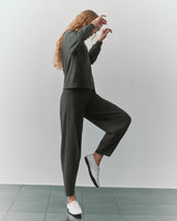 Person posing in a matching outfit and shoes on tiled floor.
