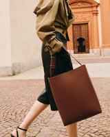 Person walking outdoors carrying a tote bag