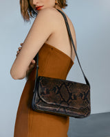 Woman wearing dress with shoulder bag featuring snake pattern.