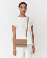 Woman standing with a crossbody bag