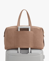Travel bag attached to luggage handle.