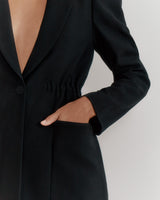 Person in a blazer with hand on hip.