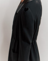Person wearing a blazer, side view, cropped at shoulders and thighs.