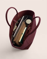 Open tote bag with books, pouches, and tech items inside.