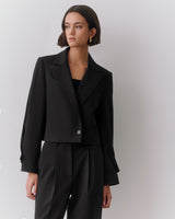 Person wearing a suit with a tailored jacket and pants.