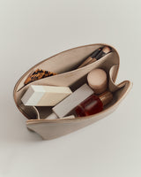 Open cosmetic bag with various beauty products inside.