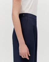 Person standing side view with hand along trouser seam.