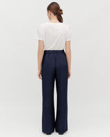 Woman standing with her back facing the camera wearing a T-shirt and wide-leg pants