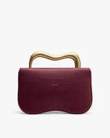 Handbag with a wavy metallic handle.