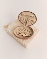 Oval jewelry case with open zipper displaying compartments inside.