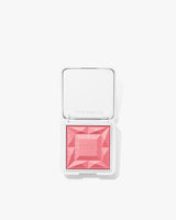 Makeup compact with raised geometric design on powder surface.