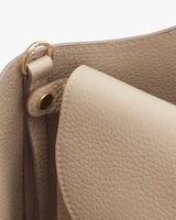 Close-up of a handbag with a focus on its handle attachment and stitching.