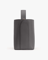 Leather backpack with handle standing against a plain background.