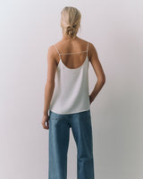 Person wearing a silk cami and jeans, facing away.