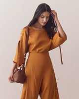 Woman in a dress touching her hair carrying a handbag