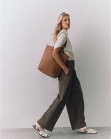 Person carrying a large tote bag, wearing wide-leg pants and sandals.