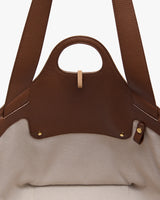 Open leather tote bag with a handle showing the interior fabric lining.