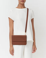 Person wearing a short-sleeve outfit with a crossbody bag
