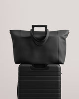 Travel bag resting on rolling luggage