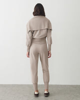 Person facing away, wearing matching pants and top in a studio setting.