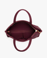 Top view of an open handbag with two handles and a zippered compartment.