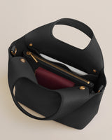 Open handbag with a zipper pocket and a red wallet inside.