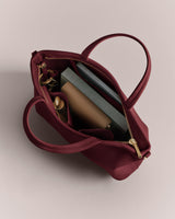 Open handbag with book, sunglasses, and water bottle inside.