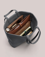 Open tote bag with organized items inside including pouches, notebook, and bottle.