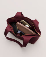 Open handbag with wallet, phone, earbuds, and small pouch inside