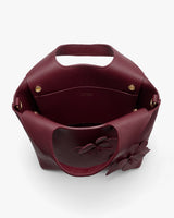 Open handbag with flower detail and handle.