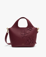 Handbag with a floral detail and round handle.