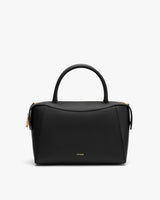 Handbag with top handles and gold accents on a plain background.