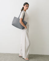 Person standing with large shoulder bag and wide-leg pants