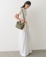 Person in a long skirt holding a handbag and looking down.