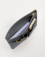 Open handbag with a book and a phone inside on a white background.