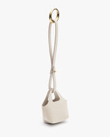 Small textured handbag with long handle and metal ring.