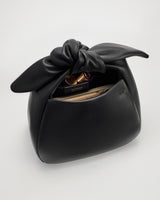Handbag with a knotted top and items peeking from the open pocket