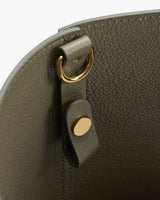Close-up of a bag's metal ring and button detail.
