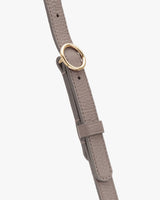 Close-up of a textured leather strap with a round metal buckle.