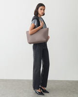 Person standing with a large shoulder bag, wearing a t-shirt and jeans.
