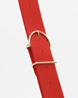 Close-up of a belt with a metal buckle and loop on a plain background.