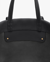 Close-up of a handbag with two handles and visible stitching.
