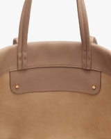 Close-up of a handbag's top handles and front detailing.