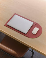 Laptop and mouse on a desk mat, next to a chair.