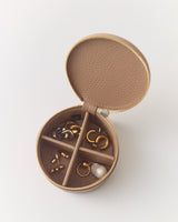 Round jewelry case with small compartments holding various earrings and rings.