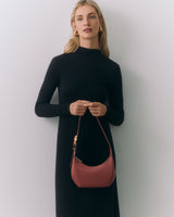 Person in a long dress holding a small handbag.