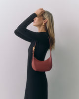 Person in dress holding small shoulder bag over shoulder.